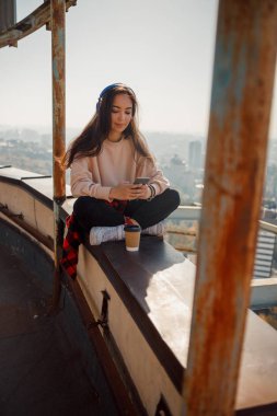 Çatıda cep telefonu kullanan gülümseyen güzel bayan.