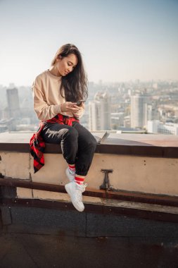 Çatıda akıllı telefonda yazan gülümseyen güzel bayan.