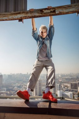 Kırmızı ayakkabılı şık adam çatıda duruyor.