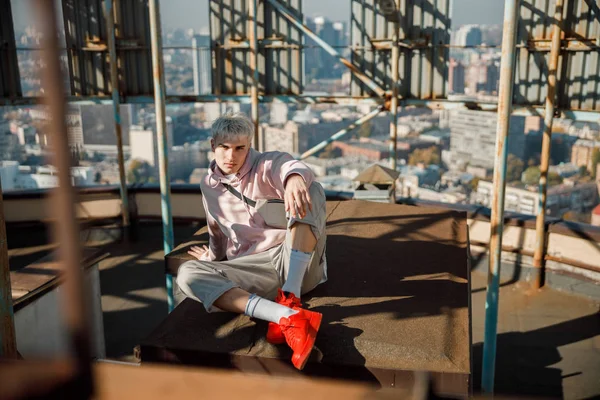 Stylish guy sitting and posing at camera on roof — Stock Photo, Image