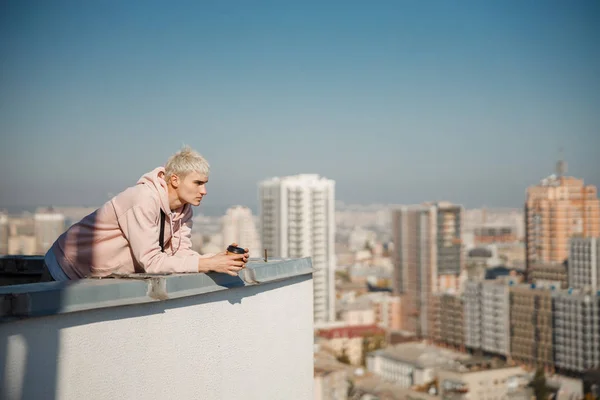 Young guy standing on roof and looking at city — Stock Photo, Image