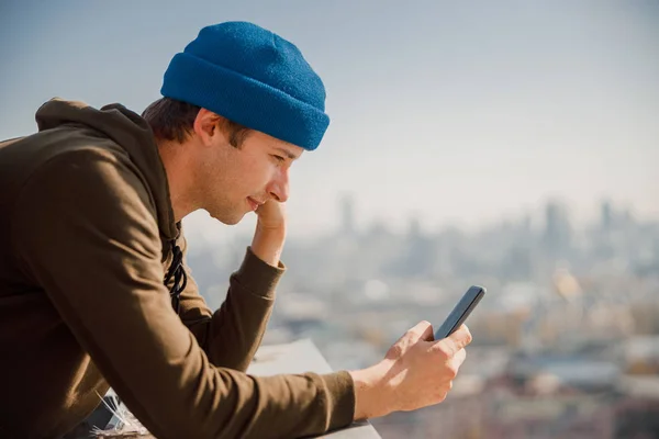 Smiling guy looking on phone screen outdoors — Stockfoto