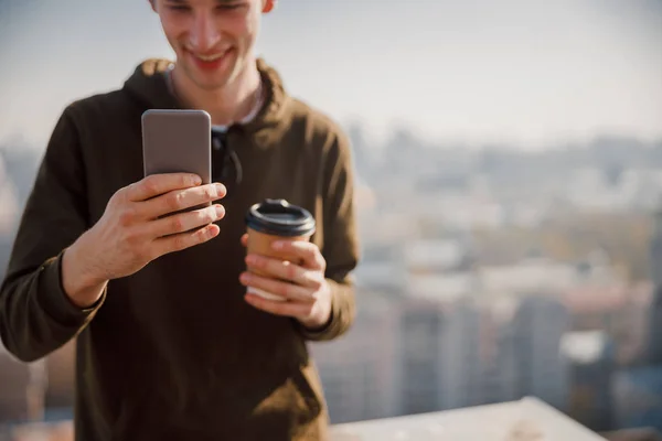 Smiling guy looking on phone screen outdoors — Stockfoto