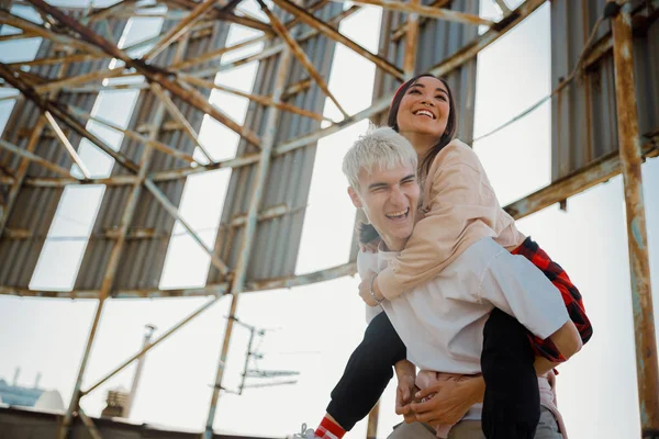 Счастливый молодой парень веселится со своей девушкой на крыше — стоковое фото