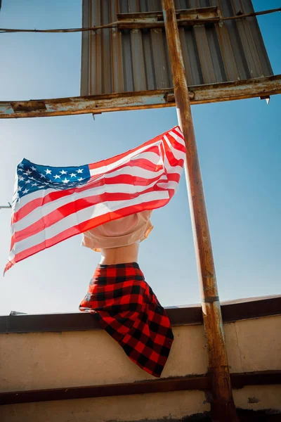 Young woman sitting with flag on roof — Stock Photo, Image