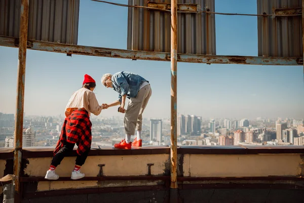 Young guy helping for his girlfriend on roof — Stock Photo, Image