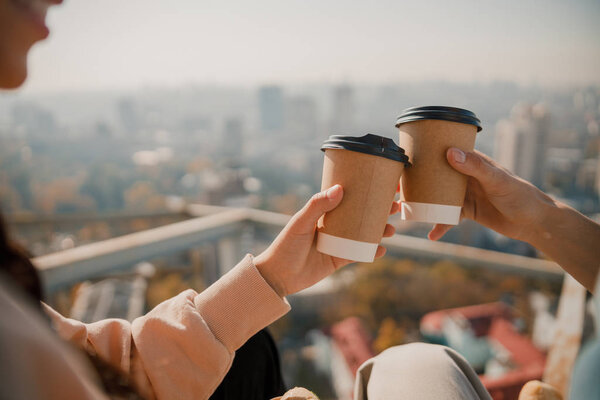 Young friends holding hot drinks on the roof
