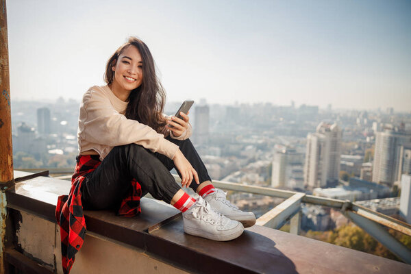 Happy pretty girl is sitting on roof while smiling