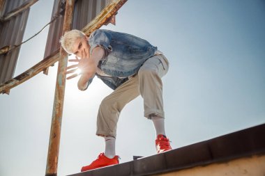 Genç adam çatıda poz verirken eğleniyor.