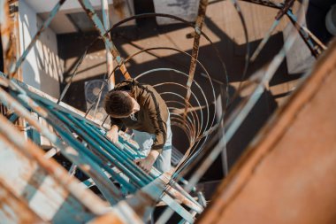 Genç adam çatıda merdivenleri çıkıyor.