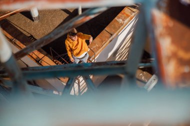 Genç adam çatıda güneşi eliyle kaplıyor.