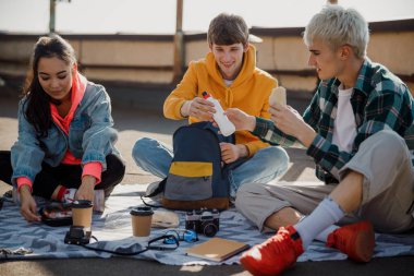 İki erkek arkadaş çatıda su şişesi tutuyor.