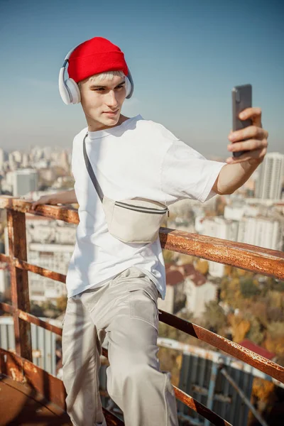 Fiatal srác piros kalapban szelfit csinál a tetőn. — Stock Fotó