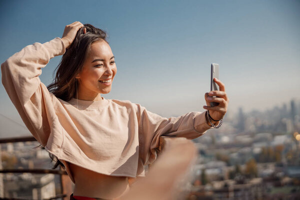 Happy Asian girl making selfie on roof