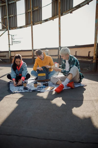 Szczęśliwi przyjaciele jedzą lunch siedząc na dachu — Zdjęcie stockowe