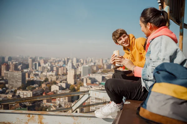 Счастливый парень смотрит на девушку, обедающую на крыше — стоковое фото