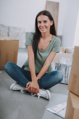 Mutlu güzel bayan yeni evinde yerde oturuyor.