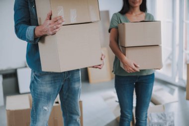 Genç çift odada karton kutular taşıyor.