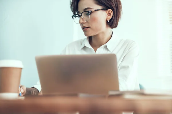 Giovane donna seduta con computer portatile in ufficio — Foto Stock