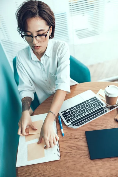 Mujer joven está doblando pegatinas en la mesa —  Fotos de Stock