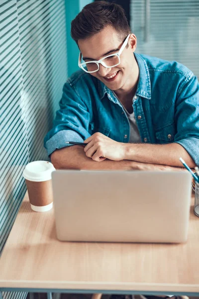 Sorrindo homem em óculos trabalhando com laptop — Fotografia de Stock