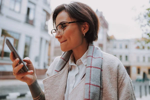 Pretty young lady is typing on smartphone in the city — Stock Photo, Image