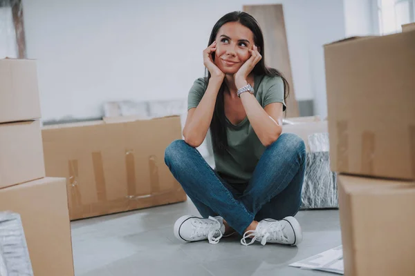 Sorridente bella donna seduta vicino alle scatole in camera — Foto Stock