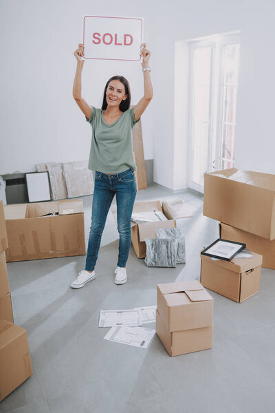 Smiling young woman standing with sol sign in room