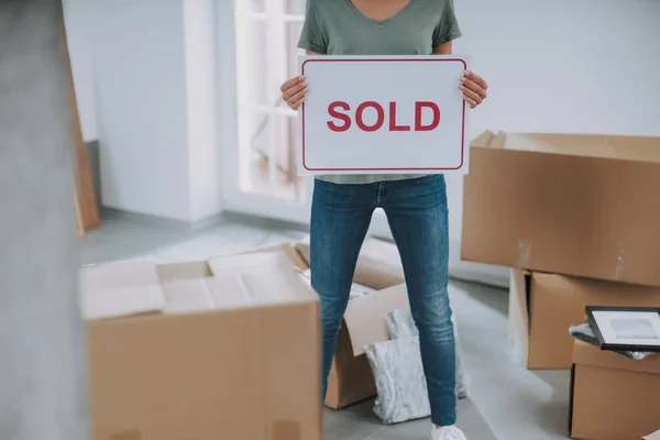 Mujer está sosteniendo letrero vendido en sus manos en casa — Foto de Stock