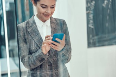 Ofis fotoğrafında gülümseyen cep telefonu kullanıcısı