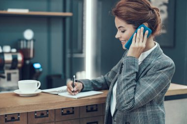 Elinde kahve ve defterle tezgahın başında dikiliyorsun.