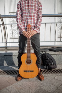 Gitarist elinde enstrümanıyla sokakta dikiliyor.