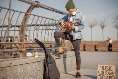 Gülümseyen genç gitarist güneşli gününde DJ 'lik yapıyor.