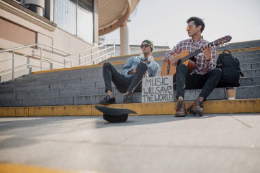 Yanında arkadaşıyla gitar çalan adam.