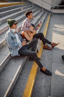 Şarkı söyleyen ve elinde kahve tutan genç adam.