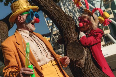 Palyaço kıyafetleri içinde açık hava fotoğraflı mutlu bir çift.