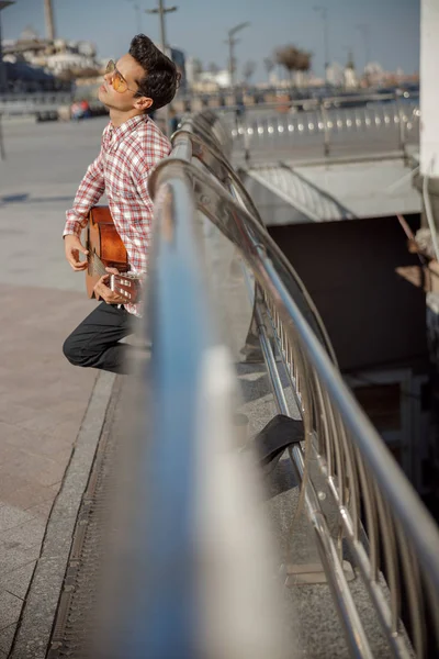 Músico tocando guitarra e de pé na cidade — Fotografia de Stock