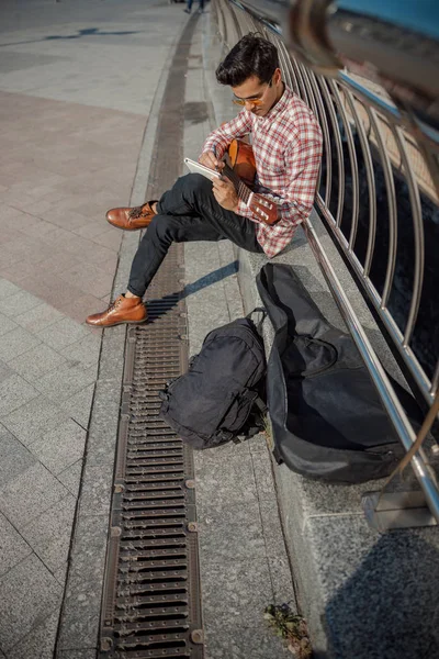 Jovem com guitarra olhando no notebook ao ar livre — Fotografia de Stock