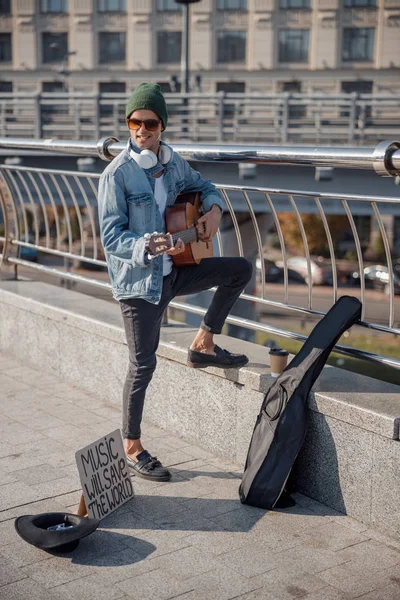 Glücklicher Gitarrist mit Hut steht mit Instrument auf der Straße — Stockfoto