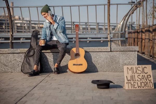 Sorrindo cara com guitarra usando smartphone na rua — Fotografia de Stock