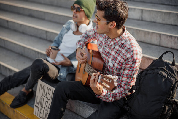 Young guitarist performing a favorite song in the city