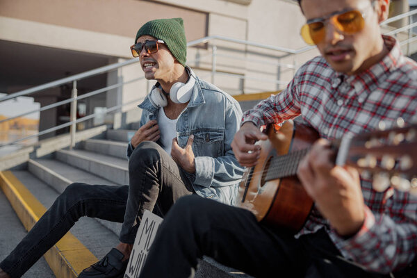 Two musicians sitting on the steps in the city