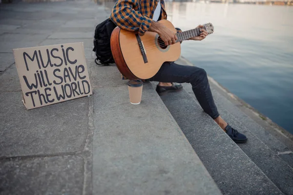 Músico tocando guitarra enquanto descansava perto do rio — Fotografia de Stock