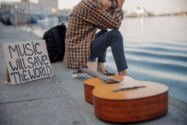 Junger Mann mit Gitarre hält Kopf an Hand — Stockfoto