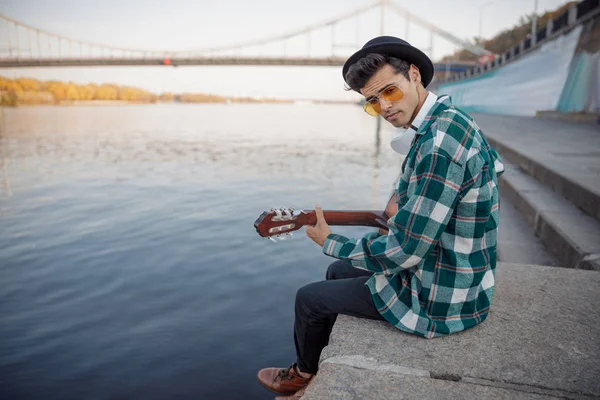 Hudebník hrající na kytaru při odpočinku u řeky — Stock fotografie