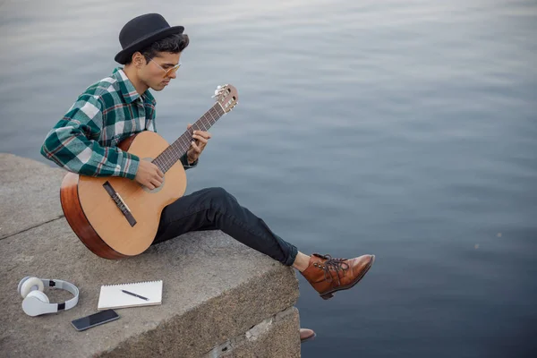 Músico masculino sentado com guitarra e notebook ao ar livre — Fotografia de Stock