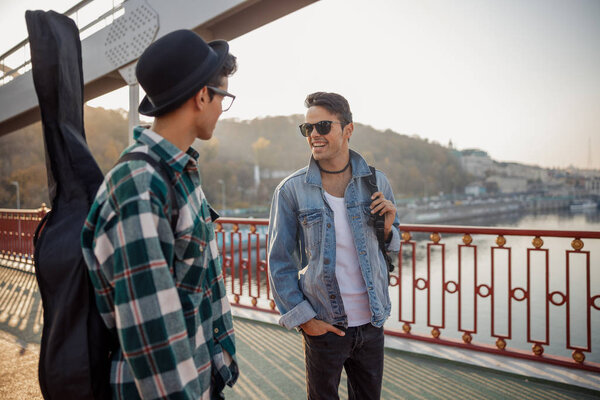 Happy young guy talking with his brother outdoors