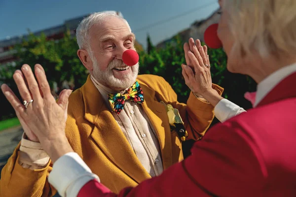 Šťastný starý muž s klaunským nosem v blízkosti milované ženy — Stock fotografie