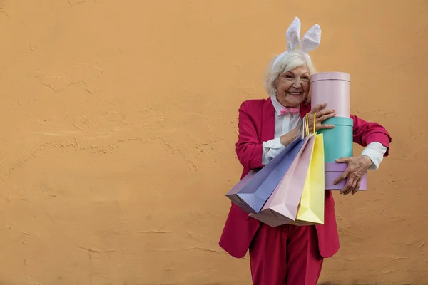 Веселая старушка в кроличьей повязке получает много подарков — стоковое фото