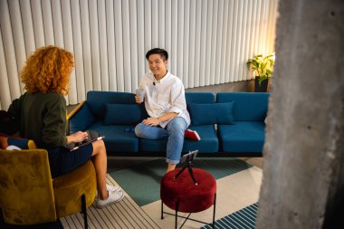 Röportaj sırasında gülümseyen adam genç kadınla konuşuyor.